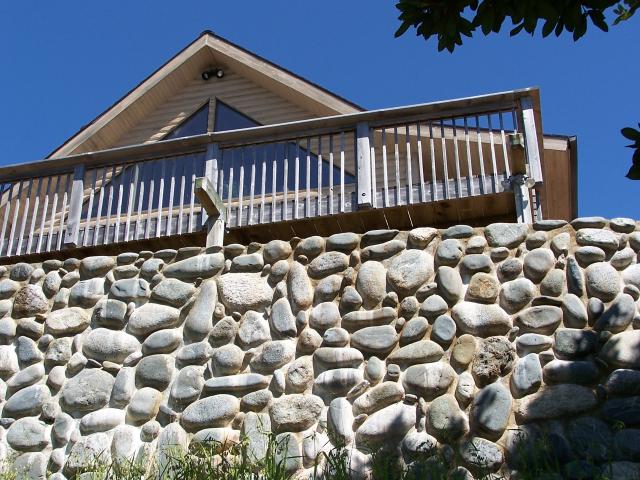 View of the house and deck from below the rock wall